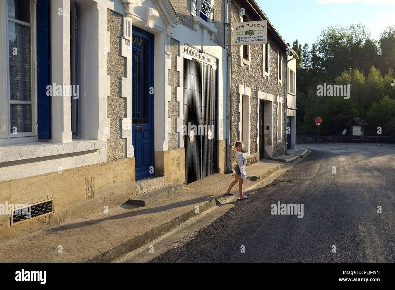 Child crossing a quiet road and throwing a long shadow on a summer evening in Eymet, southwestern France 2018. Stock Photo