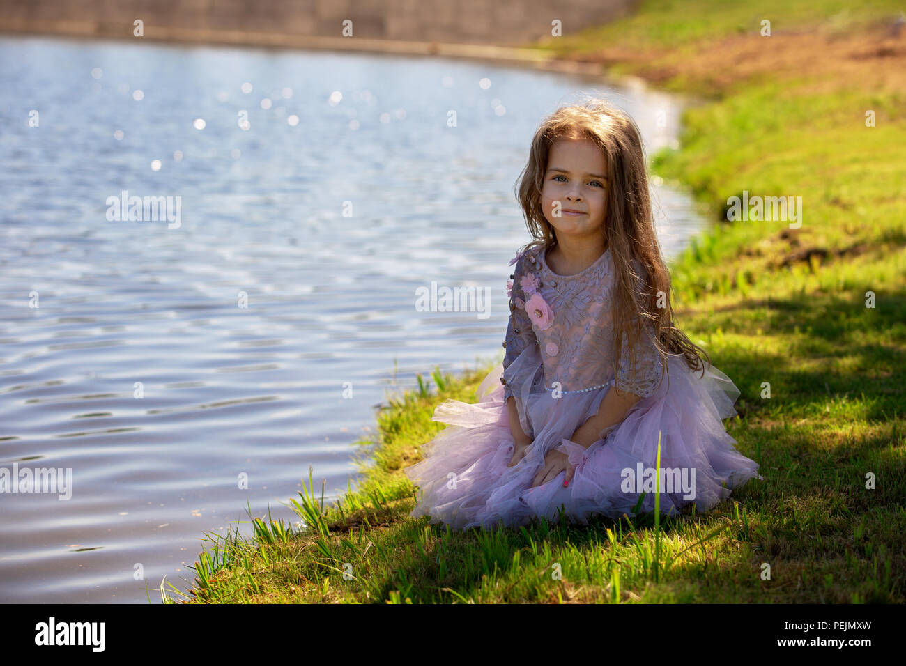 Portrait of a beautiful little girl in summer on nature. Child on the shore of the lake Stock Photo