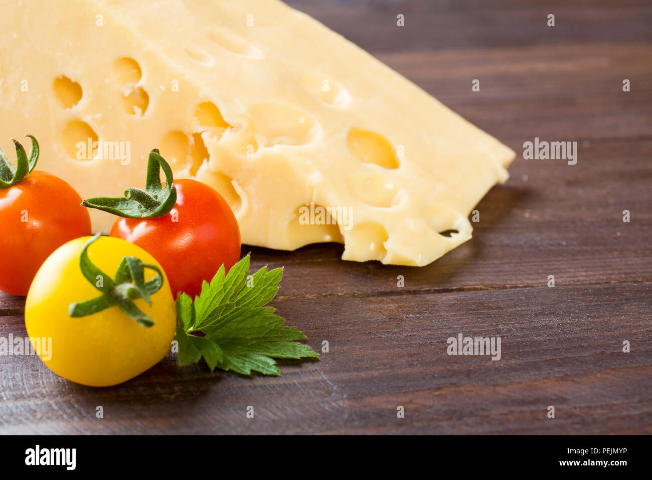 https://c8.alamy.com/comp/PEJMYP/cheese-and-tomatoes-on-dark-wooden-background-with-copy-space-PEJMYP.jpg
