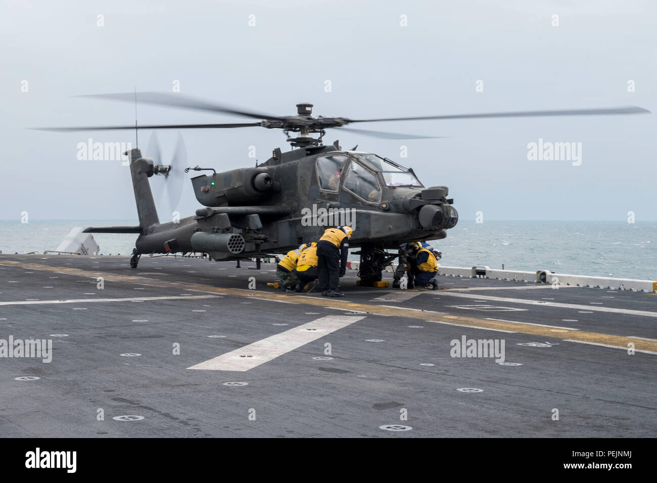 151206-N-ZZ999-037 ARABIAN GULF (Dec. 6, 2015) Sailors chock and chain an U.S. Army AH-64D Apache helicopter of the 185th Theater Aviation Brigade (TAB), Task Force Pale Riders, to the flight deck of the amphibious assault ship USS Kearsarge (LHD 3). Kearsarge is the flagship for the Kearsarge Amphibious Ready Group (ARG) and, with the embarked 26th Marine Expeditionary Unit (MEU), is deployed in support of maritime security operations and theater security cooperation efforts in the U.S. 5th Fleet area of operations. (U.S. Navy photo by Mass Communication Specialist Seaman Apprentice Dana D. L Stock Photo