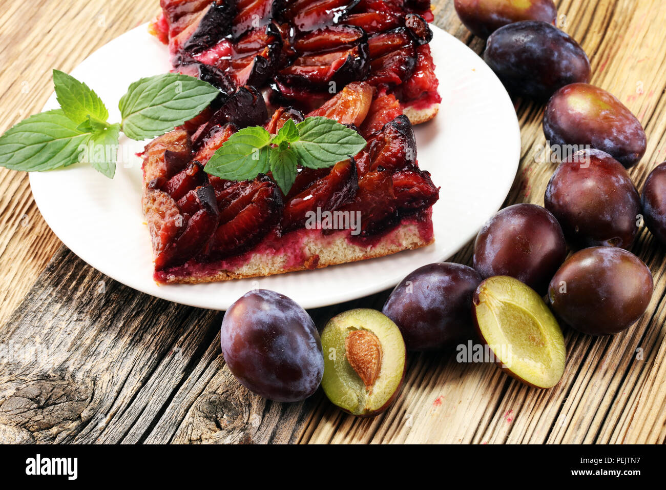 Rustic plum cake on wooden background with plums around Stock Photo