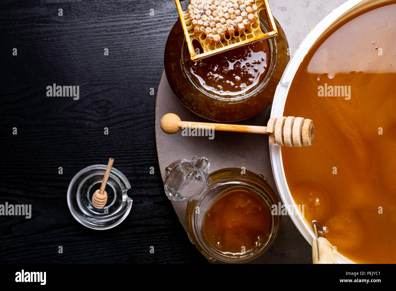 Honey in jar and big bucket, and wooden stick Stock Photo Alamy