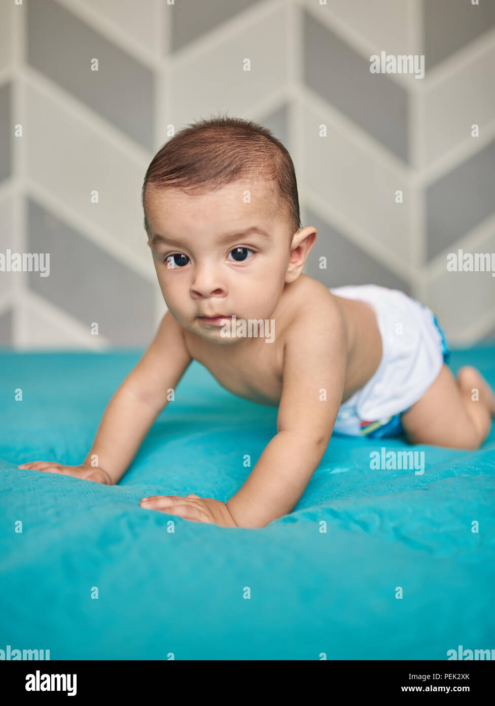 Baby boy on blue bed blanket in room. Baby boy in cloth diaper Stock