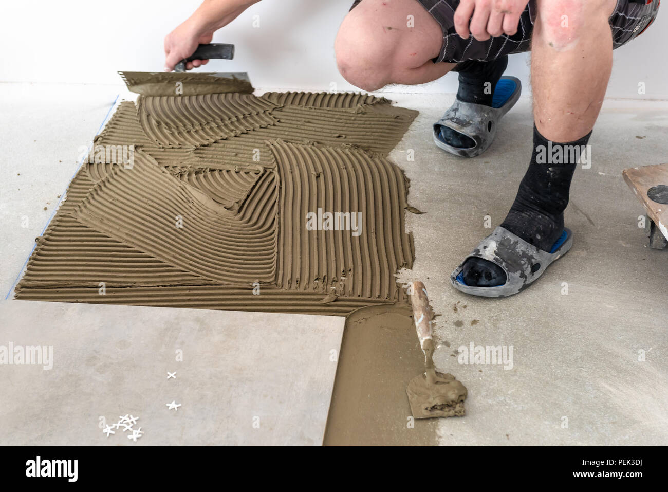 The hands of the tiler are laying the ceramic tile on the floor Stock
