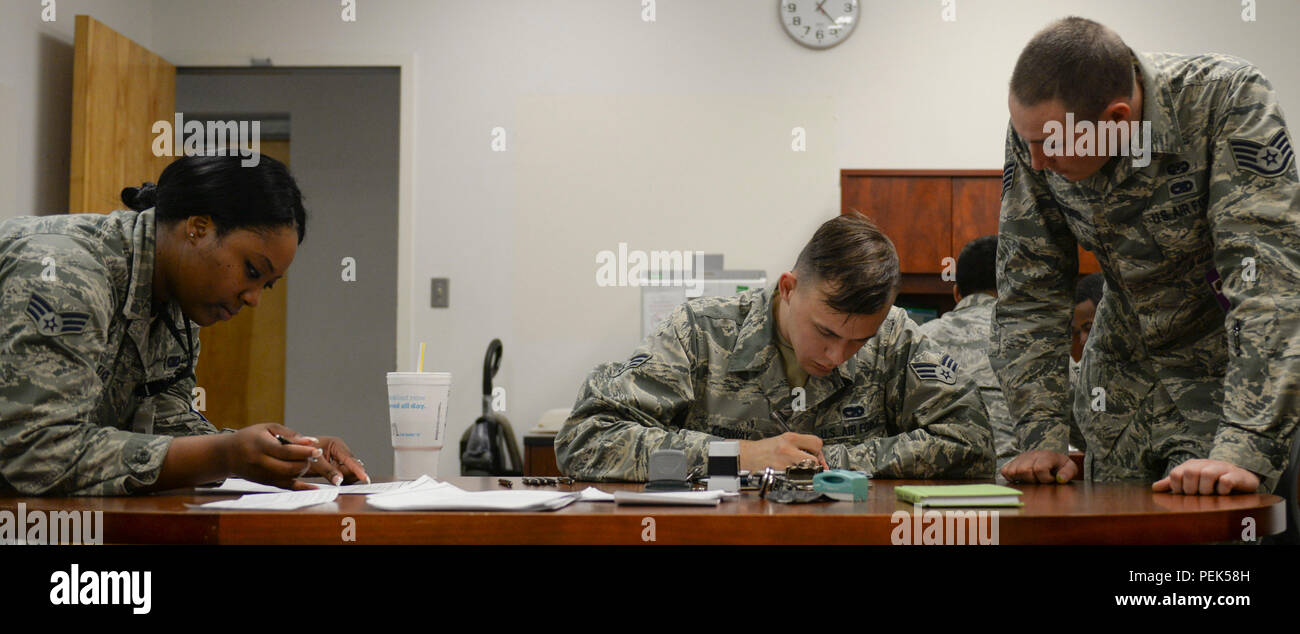 Staff Sgt. Timothy Mefford, a 49th Judge Advocate paralegal, assists Senior Airman Ryan Walker, a 49th administration journeyman, and Senior Airman Austin Conway, a 49th vehicle maintenance journeyman, with a Power of Attorney form during the Legal Hawk Outreach Program visit to the 49th Material Maintenance Support Squadron at Holloman Air Force Base, N.M., Dec. 4, 2015. The outreach program was created to provide quality legal assistance to those who were having difficulty making it to the legal office. (U.S. Air Force photo by Staff Sgt. E’Lysia A. Wray) Stock Photo