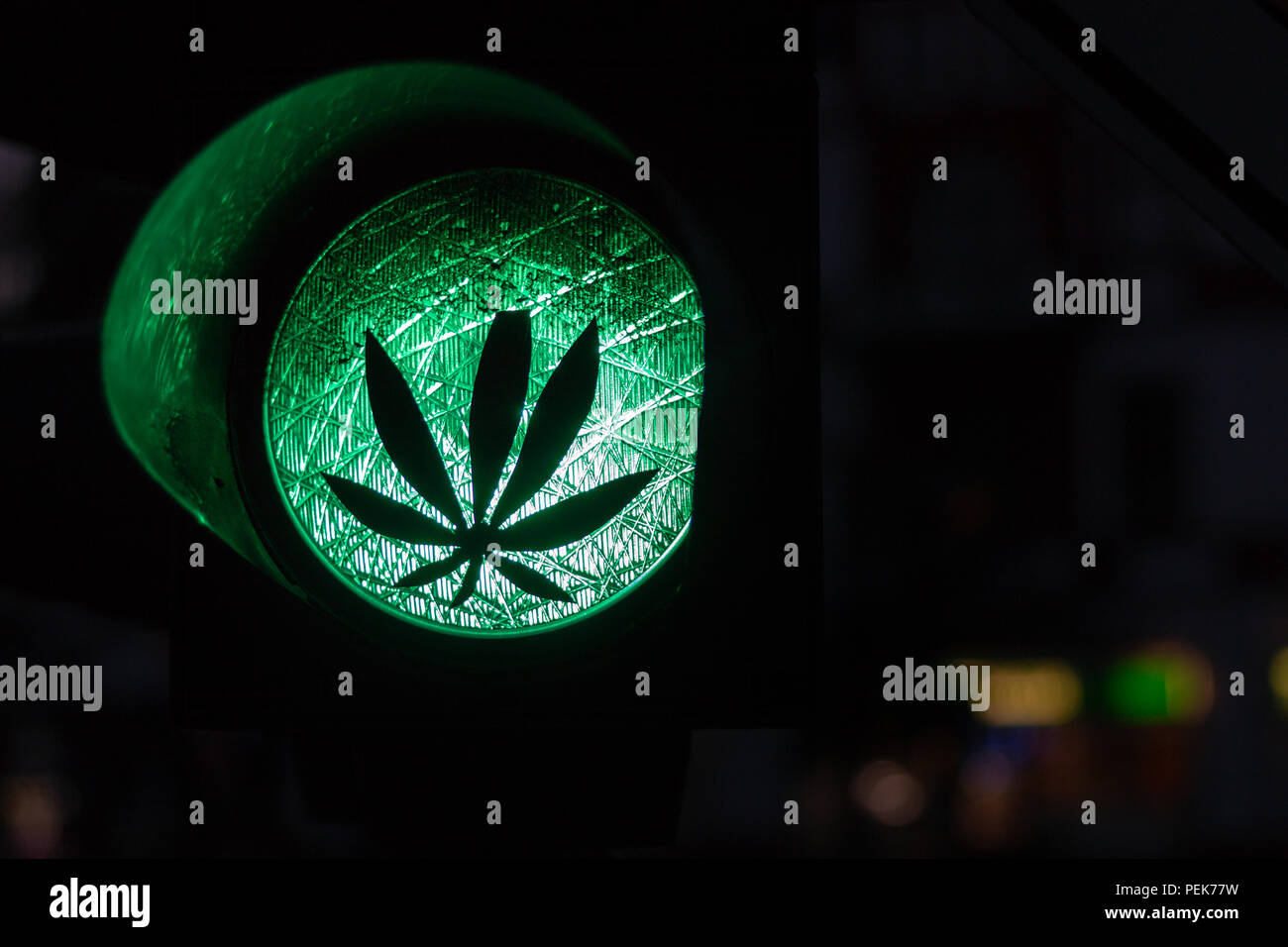 A sticker of a plant on a green traffic light as a symbol of the legalization of cannabis or marijuana Stock Photo