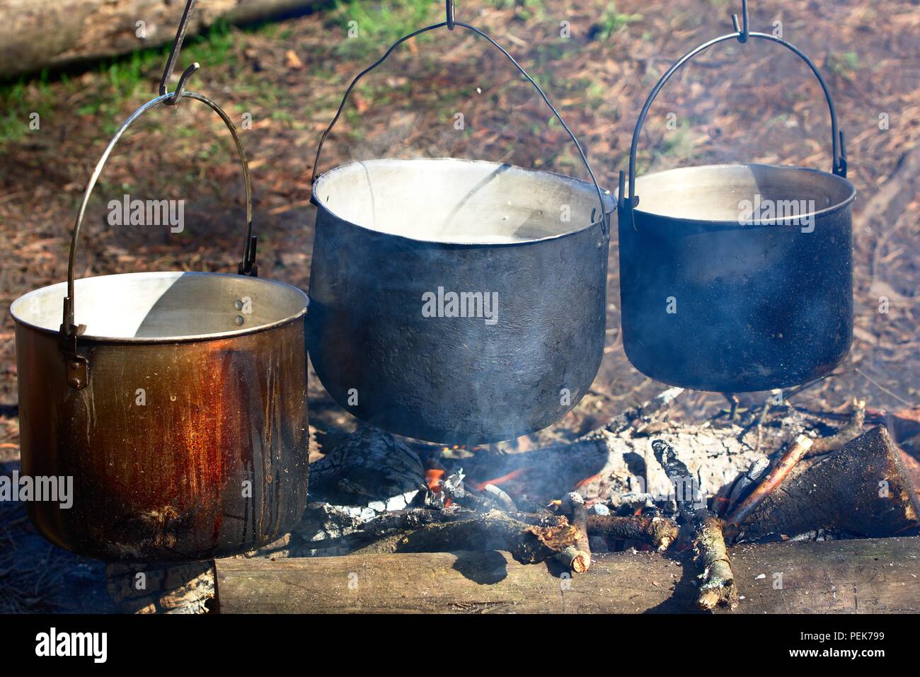 Three kettles hanging above fireplace outdoors Stock Photo Alamy