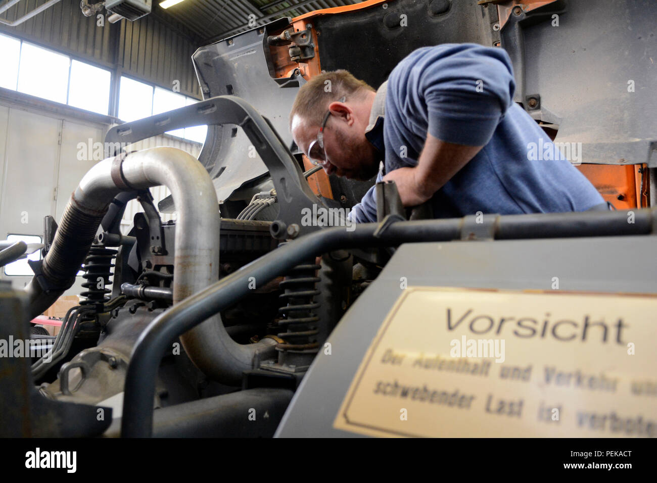 Hans-Juergen Fischer, a mechanic with the 6981st Civilian Support Group, 2nd Signal Brigade, fixes an engine on a cargo truck in the unit's motor pool Dec. 11, 2015 at Germersheim Army Depot, Germany. Stock Photo
