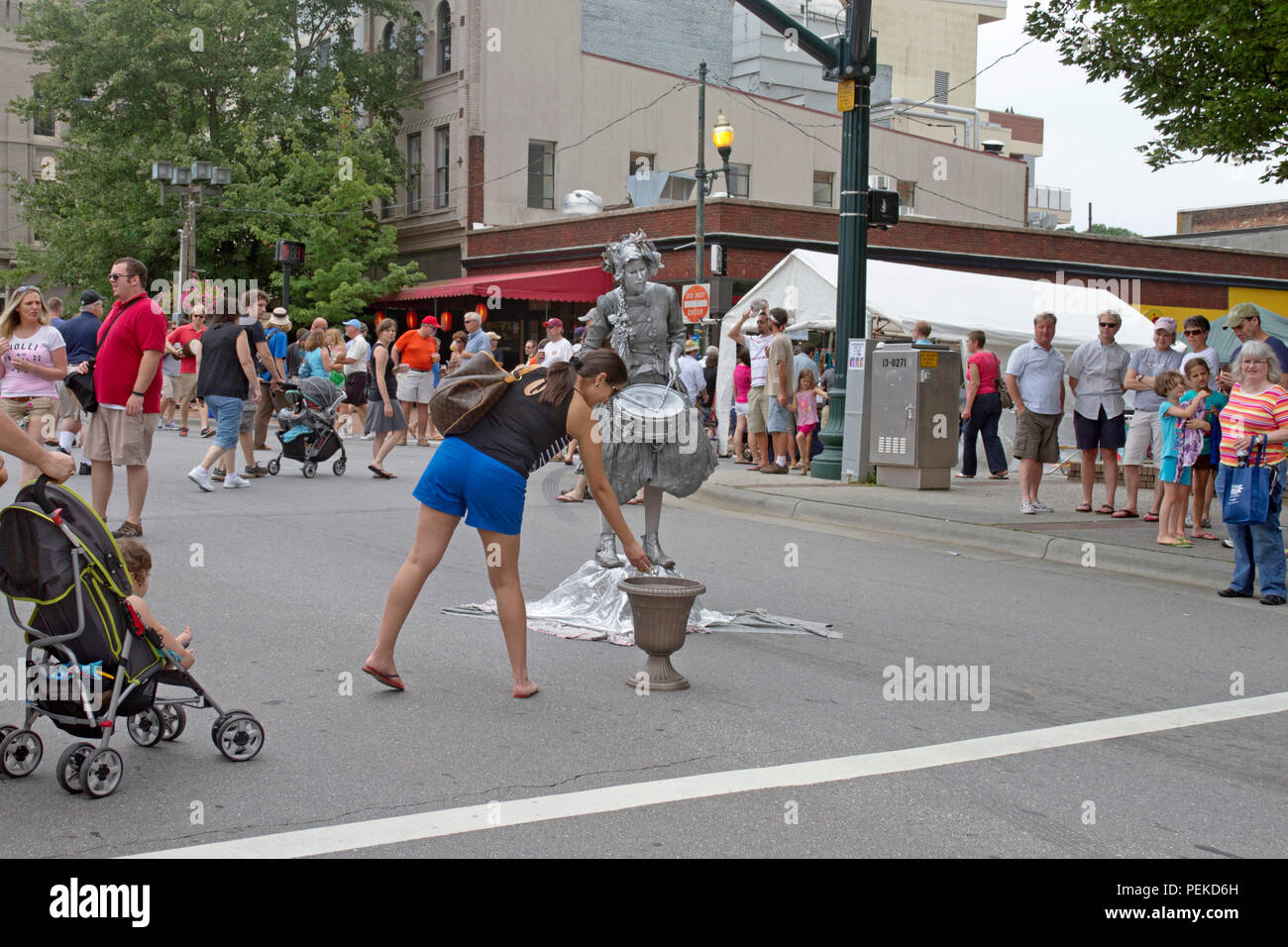 ASHEVILLE, NC, USA - JULY 27, 2013: A woman tips a living statue performer depicting an old fashioned, drummer at the last bele Chere Festival in 2013 Stock Photo