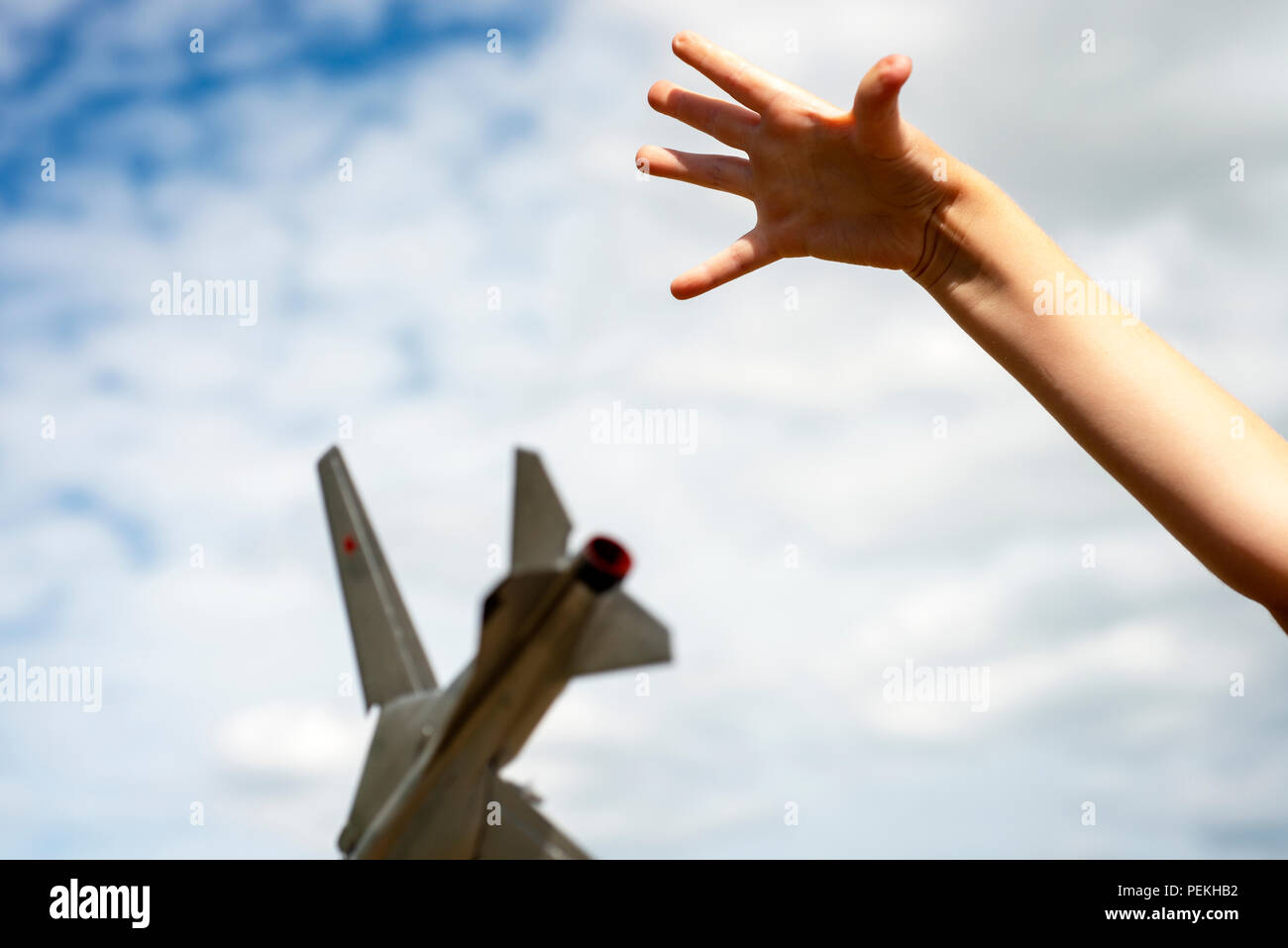 Childs hand dropping a scale model of a Russian Mig-23 fighter jet Stock Photo