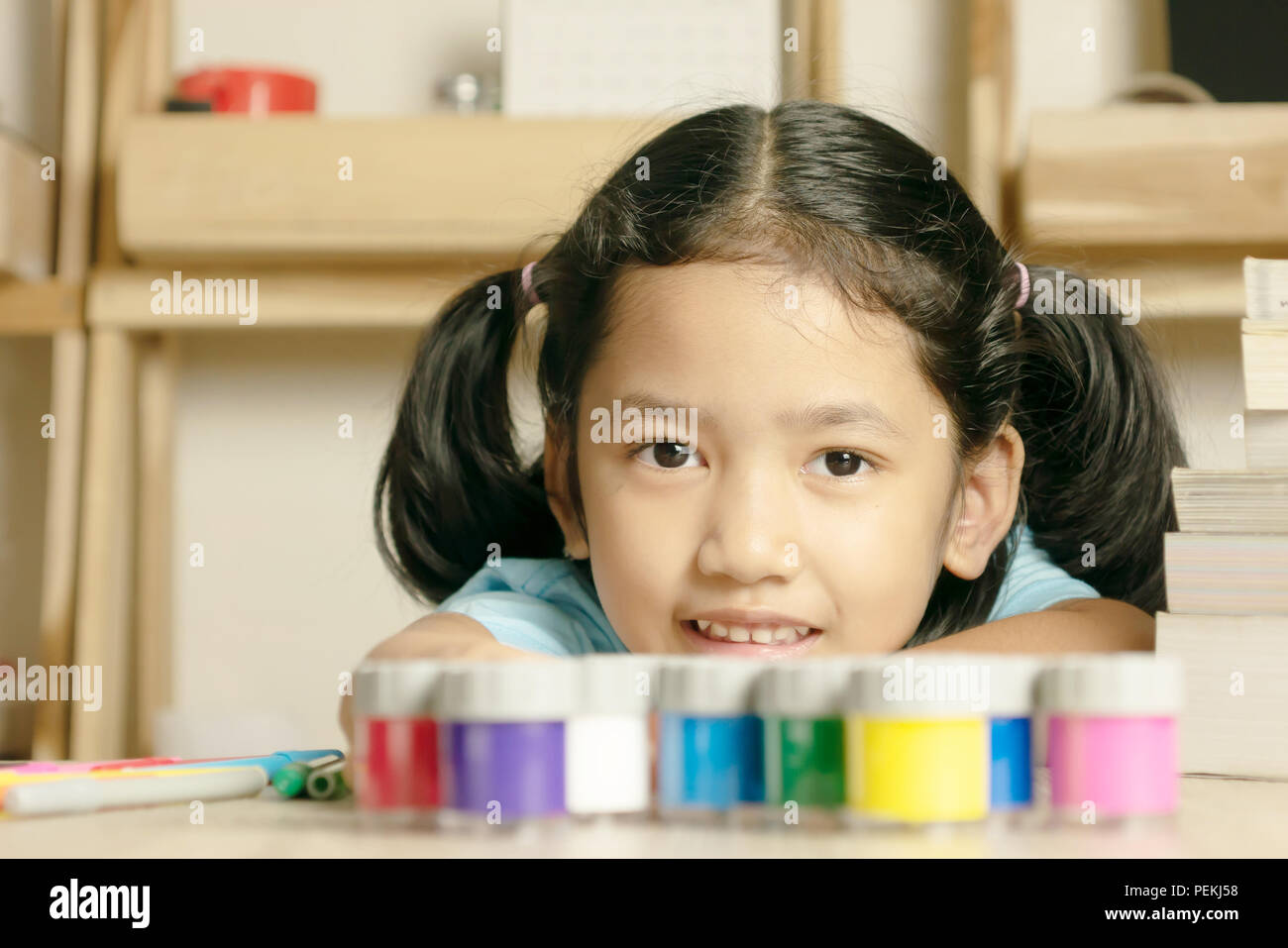 Little girl looking forward and smilling. Color group and book on the