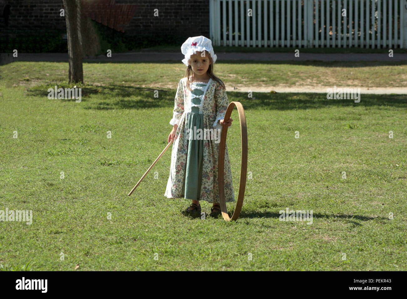 Little child playing hoop and stick in Colonial Williamsburg, Virginia Stock Photo