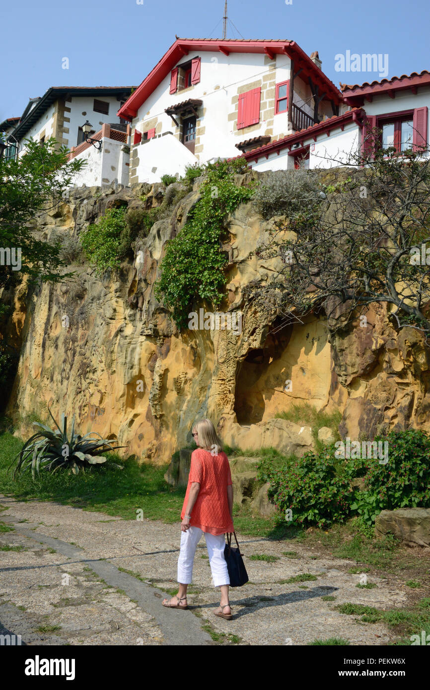 Woman walking along the beach at Algeria by sandstone cliffs, Bilbao, Spain Stock Photo