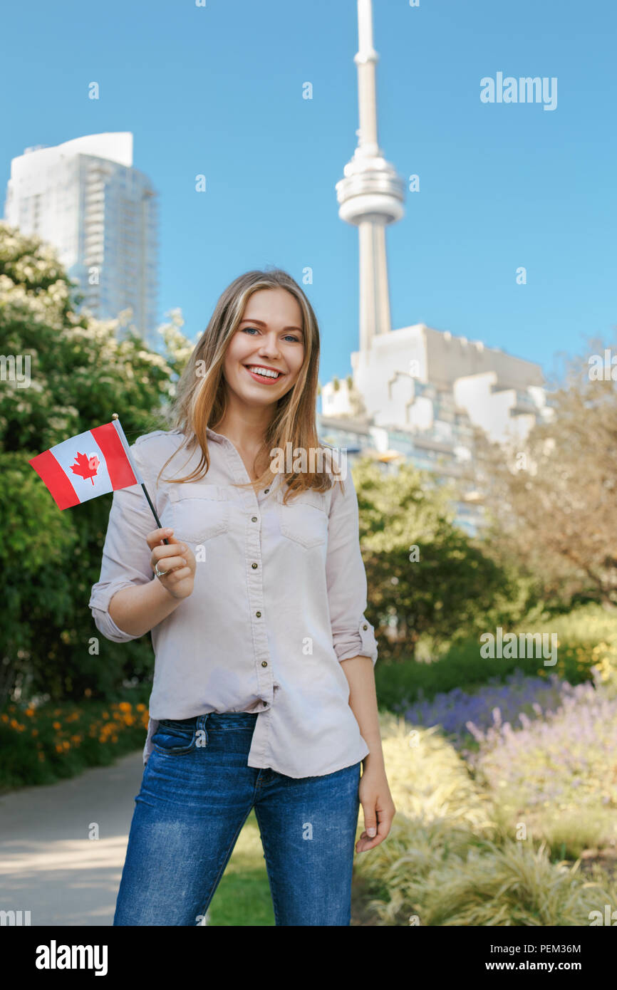 Portrait of beautiful smiling white blonde Caucasian woman holding waving  Canadian flag with red maple leaf, outside in Toronto city near CN Tower,  lo Stock Photo - Alamy