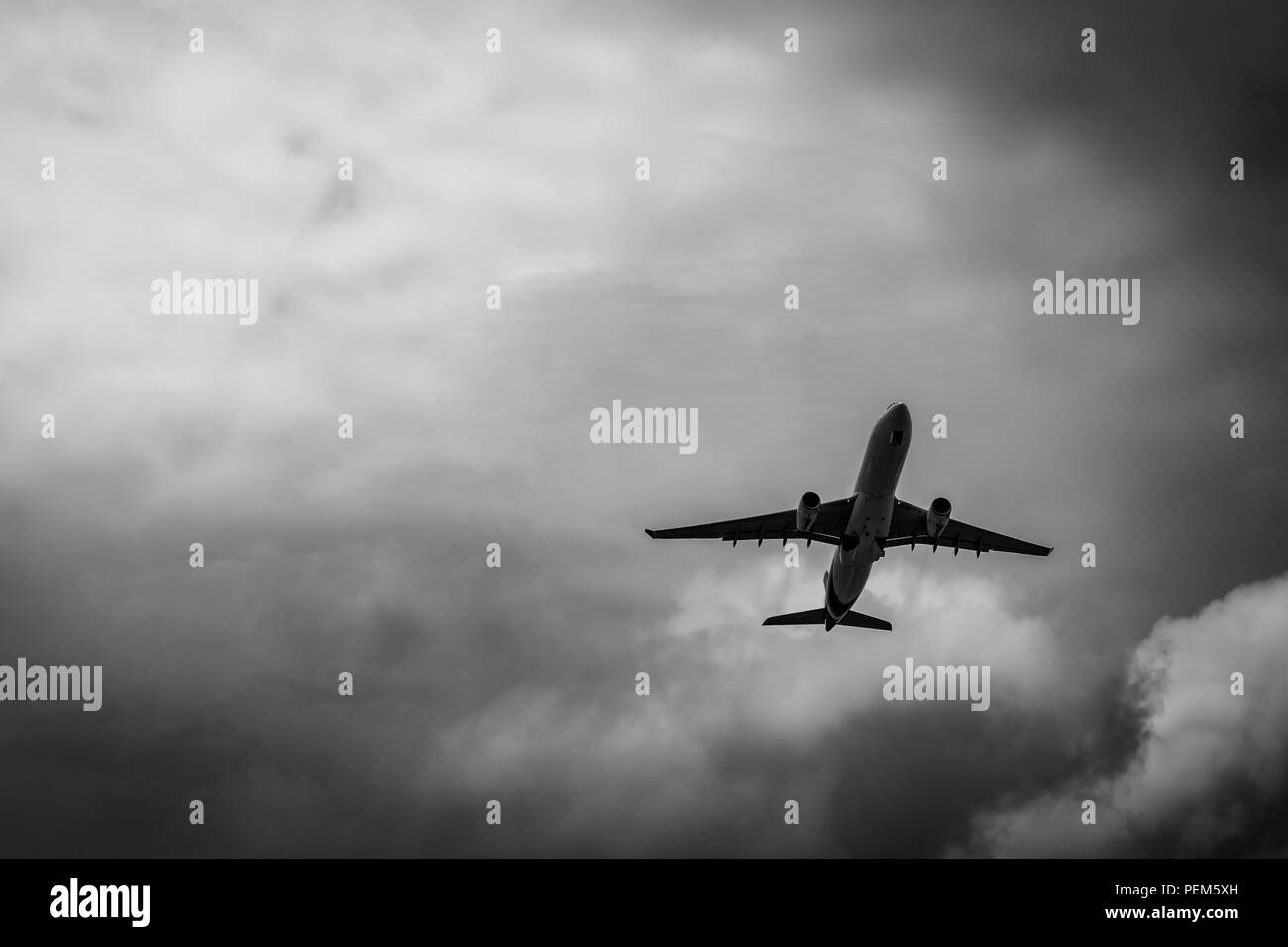 Commercial airplane on grey sky and clouds with copy space. Failed vacation. Hopeless and despair concept. Moody sky and transport plane. Sad emotiona Stock Photo
