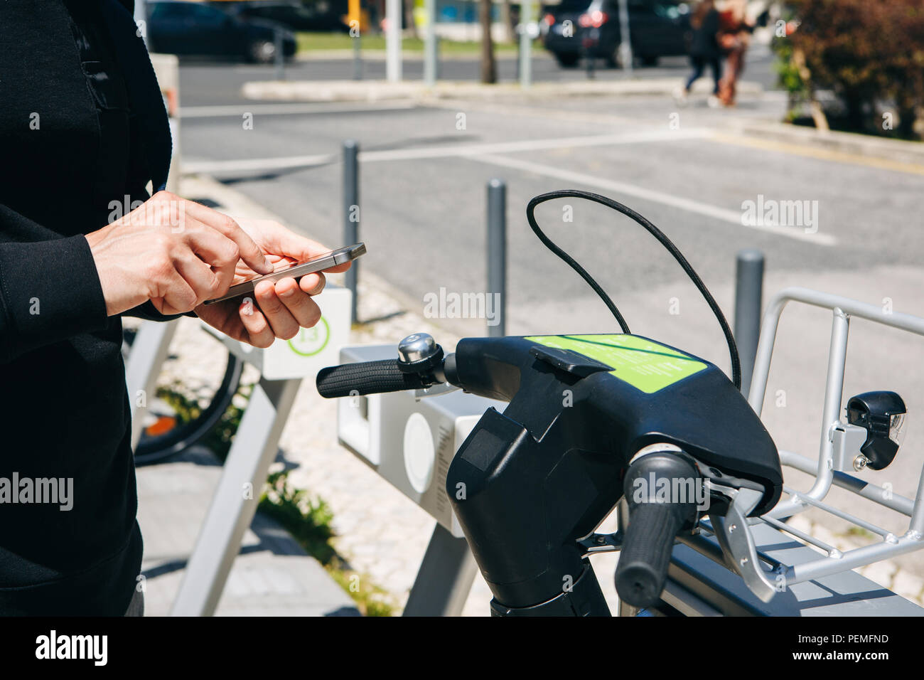 Man or tourist rents bicycle or city alternative ecological transport using the mobile app on your phone. Or he simply dials a number and calls or uses the Internet on the street. Stock Photo