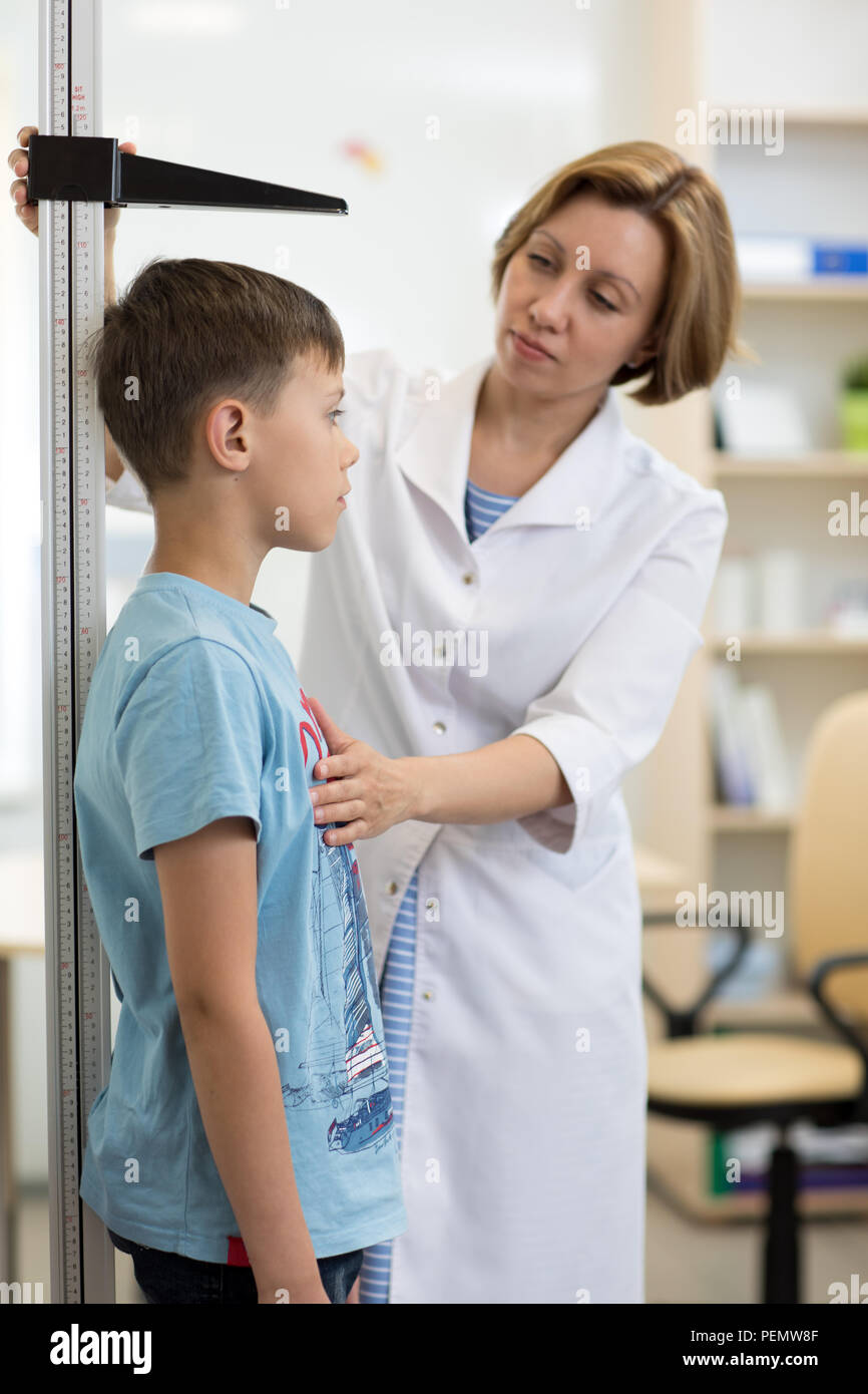 Female doctor measuring height of boy in clinic Stock Photo