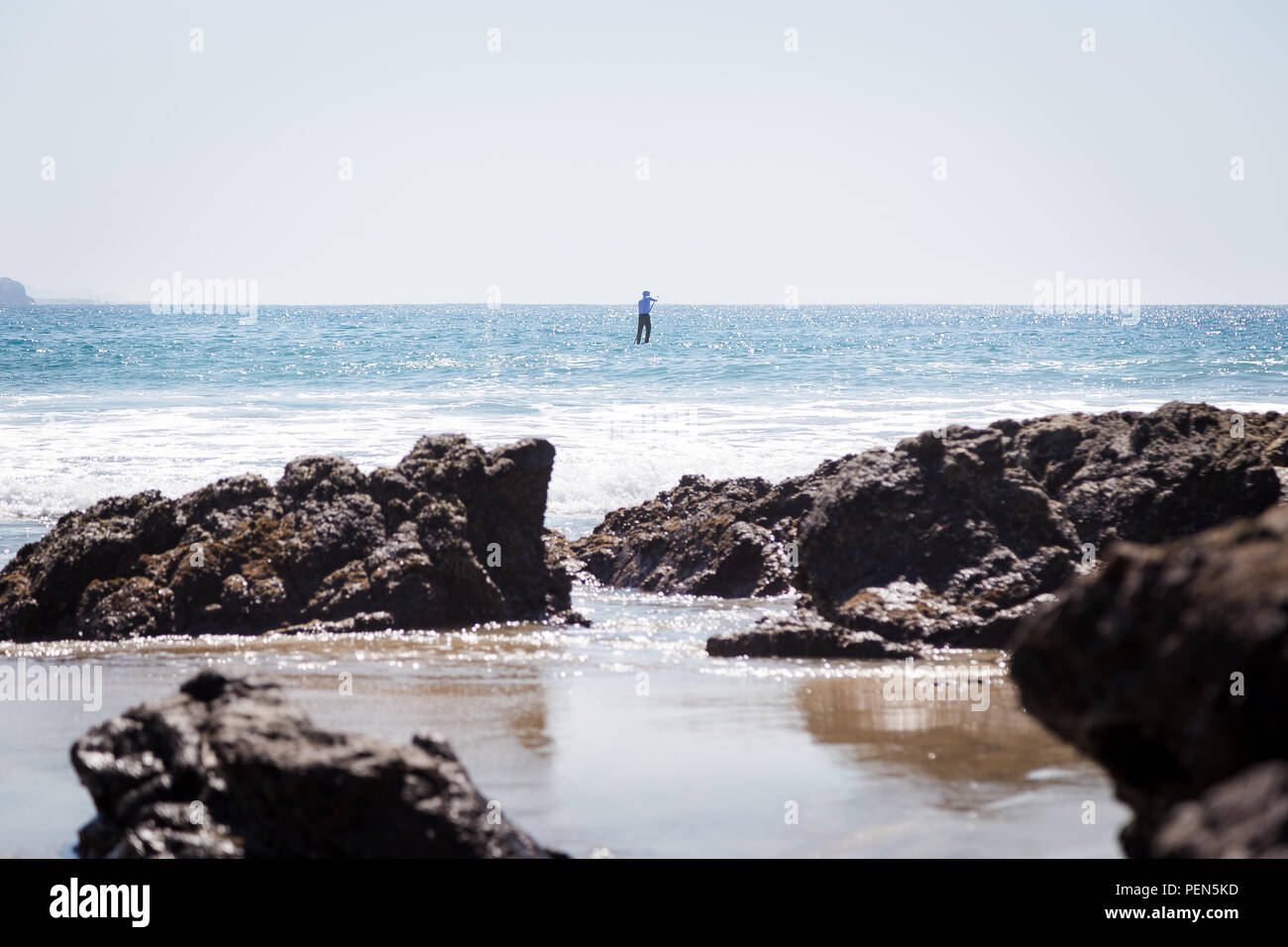 A solitary paddle-boarder out on the ocean. Stock Photo