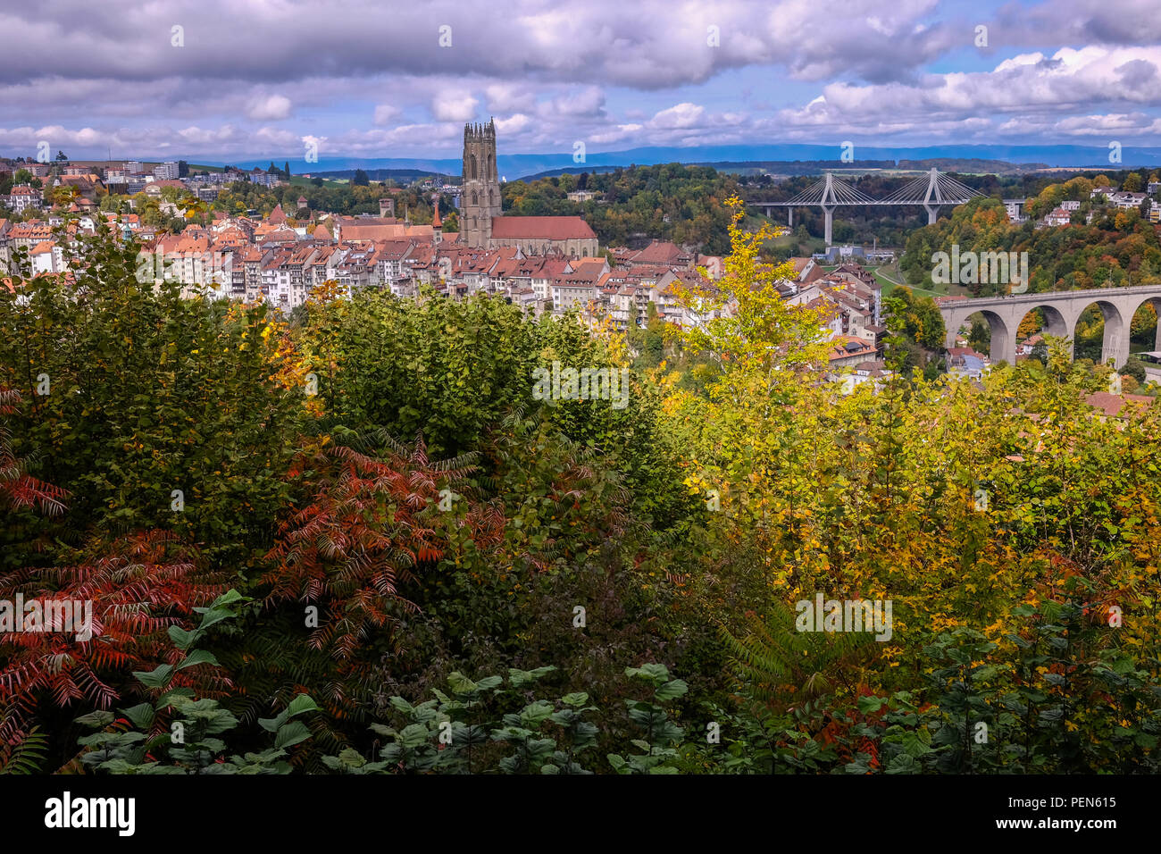 Panoramic view of the city of Fribourg, Switzerland, with the Saint-Nicolas cathedral in the center and autumnal trees in the foregound Stock Photo