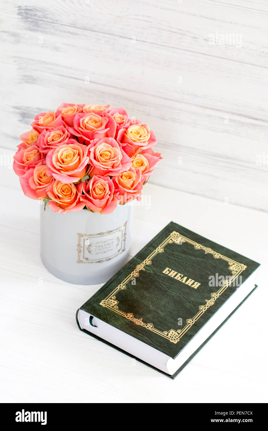 Roses in a round box and the Bible. Beautiful pink roses on a white ...