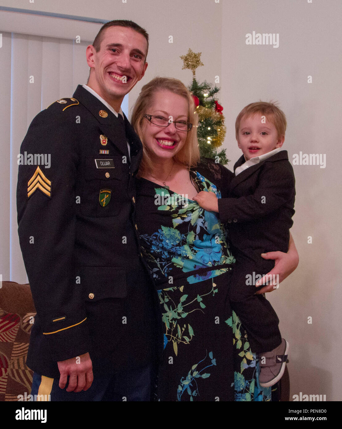 Sgt. Scott Olijar, his wife, Jennifer, and their son pose in front of their Christmas tree at their donated condominium on December 23, 2015. Through a partnership with the Illinois Housing Development Authority (IHDA) and the city of Berwyn, the Olijars received a fully furnished, permanent new home. (U.S. Army photo by Sgt. Elizabeth Barlow/Released) Stock Photo