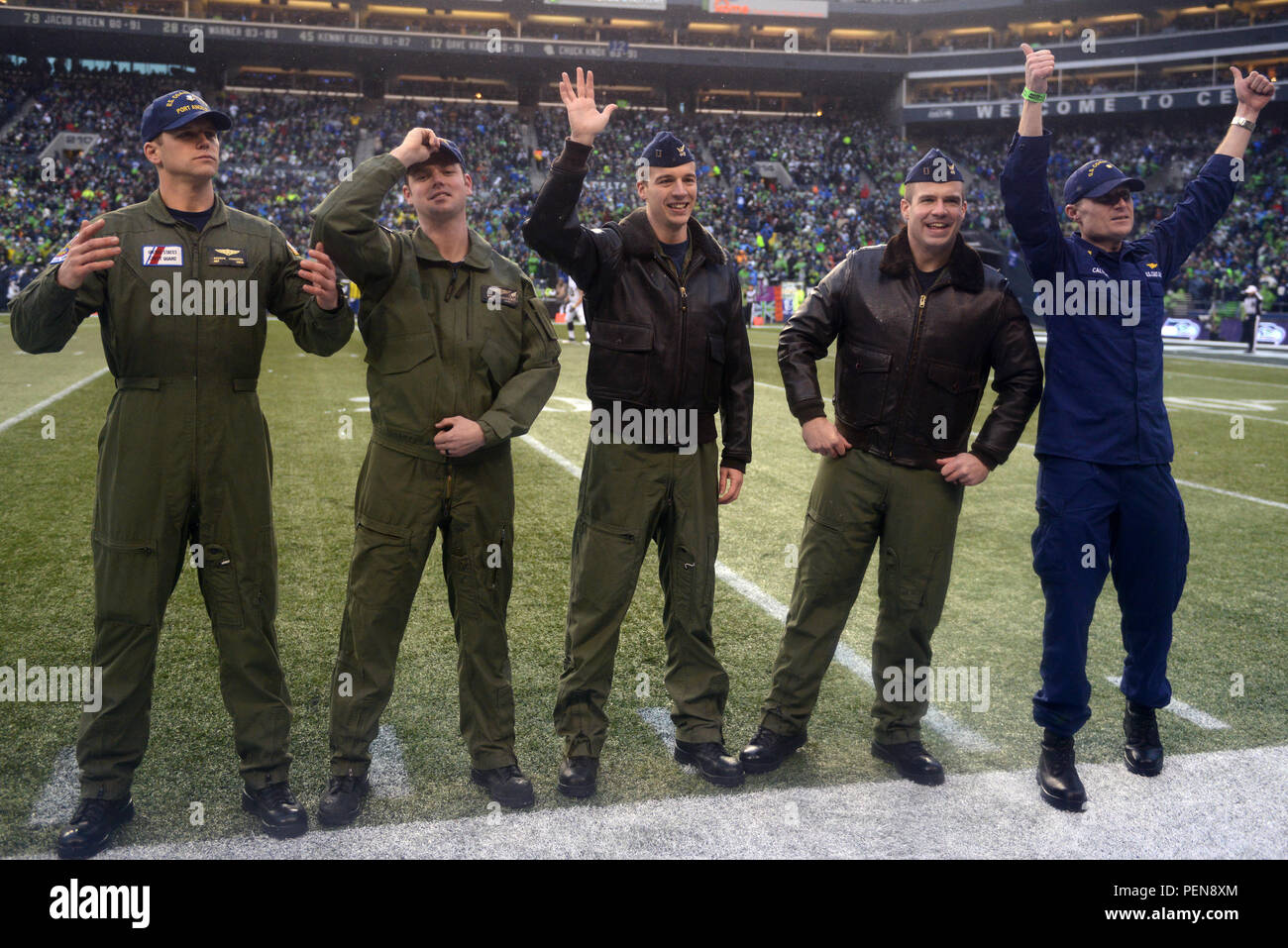 Petty Officer 2nd Class Andrew Johnston, Petty Officer 2nd Class Bryan McCarthy, Lt. Jared Hylander, Lt. Jake Marks and Lt. Cmdr. Matt Calvert, MH-65 Dolphin helicopter crewmen from Coast Guard Air Station Port Angeles, Wash., rally Seahawks fans from the CenturyLink field in Seattle during a Seattle Seahawks game Dec. 27, 2015. The crews did a flyover in two Dolphin helicopters before the game during the singing of the National Anthem while members from the Coast Guard and other military branches presented the American flag on the field. (U.S. Coast Guard photo by Seaman Sarah Wilson) Stock Photo