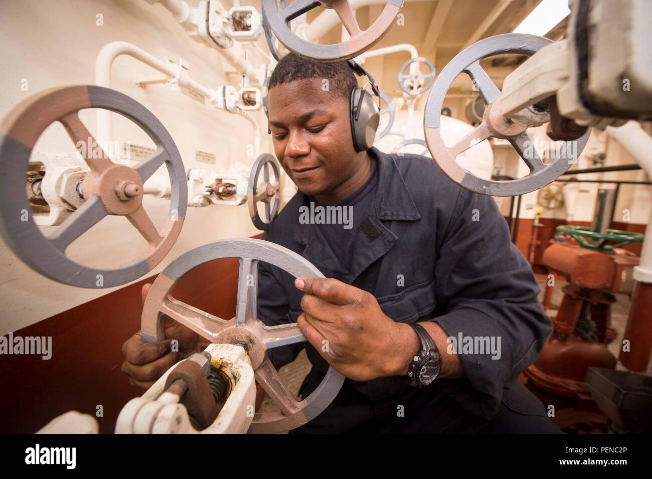 151218-N-GR361-187   RED SEA (Dec. 18, 2015) Fireman Apprentice Oscine Banton, from Virginia Beach, Va., checks a valve in an auxiliary machinery space aboard the amphibious transport dock ship USS Arlington (LPD 24). Arlington is part of the Kearsarge Amphibious Ready Group (ARG) and, with the embarked 26th Marine Expeditionary Unit (MEU), is deployed in support of maritime security operations and theater security cooperation efforts in the U.S. 5th Fleet area of operations. (U.S. Navy photo by Mass Communication Specialist 3rd Class Kaleb R. Staples/Released) Stock Photo