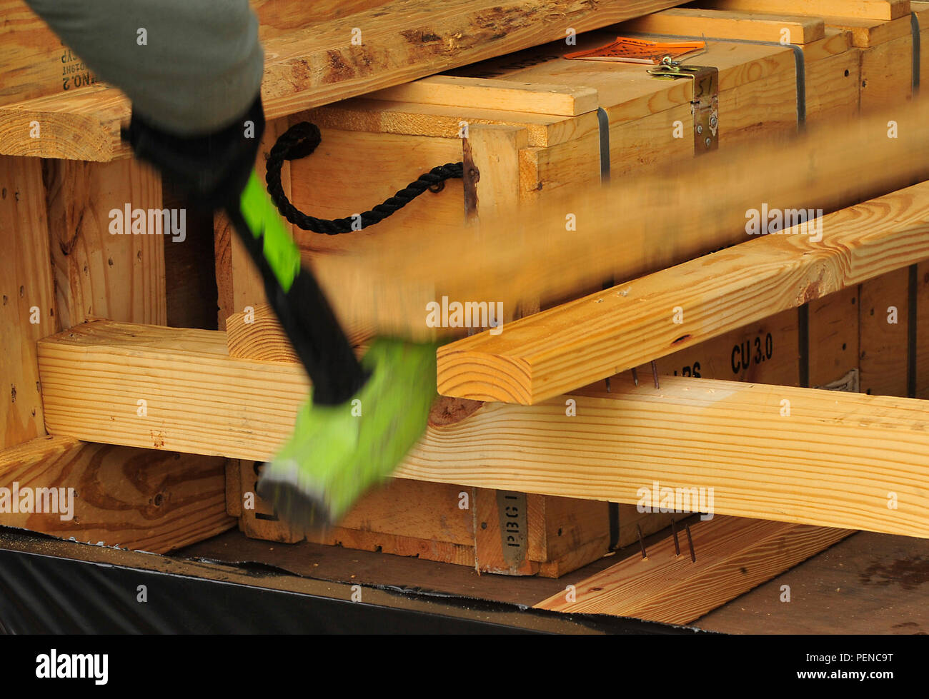 An 86th Munitions Squadron Airman breaks apart wood framing to release crates containing explosives Dec. 8, 2015, at Ramstein Air Base, Germany. Ramstein is the hub for shipping munitions to NATO partners. (U.S. Air Force photo/Airman 1st Class Larissa Greatwood) Stock Photo