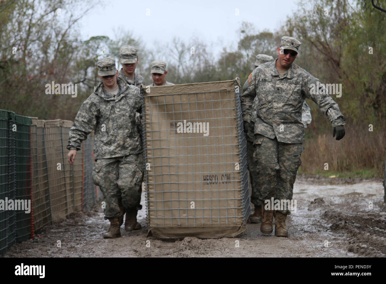 Louisiana National Guard Spc. Scott Mouton, of Baton Rouge, Spc. Mason  Guidry, of Breaux Bridge, and other Guardsmen carry a HESCO barrier on  Avoca Island near Morgan City, La., Jan. 9, 2016.