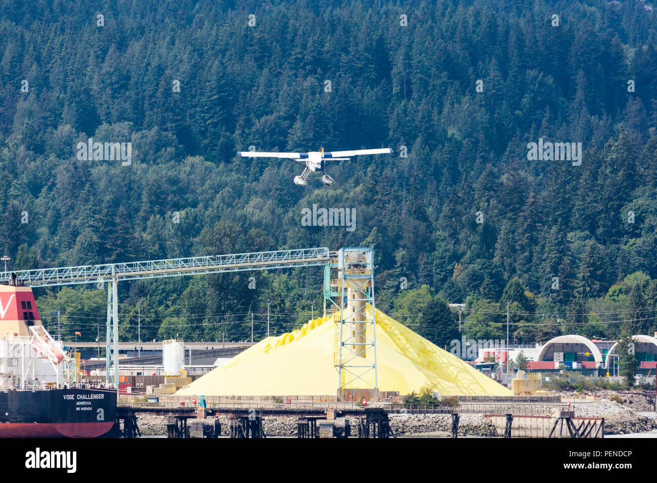 A tourist seaplane taking off in quite close proximity to the pile of sulphur in the harbour at North Vancouver, British Columbia, Canada Stock Photo