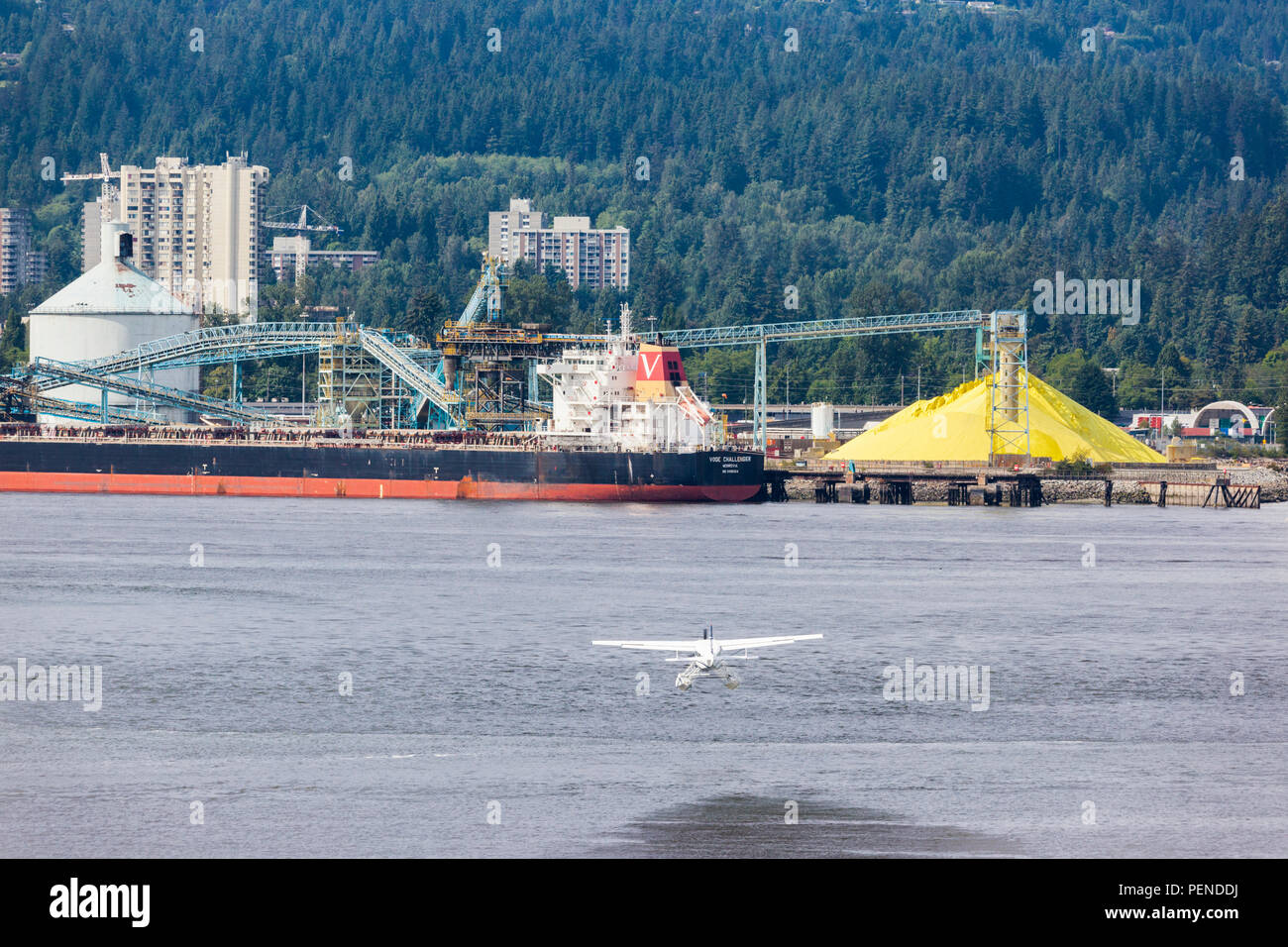 A seaplane taking off towards the pile of sulphur in the harbour at North Vancouver, British Columbia, Canada Stock Photo