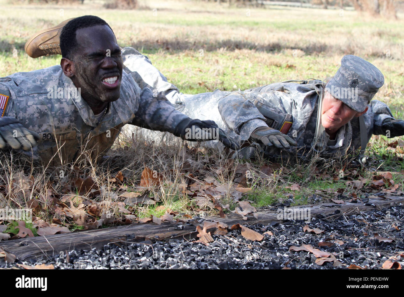 Staff Sgt. Timothy Boutte, the senior mechanic for Company D, 949th Brigade Support Battalion, 56th Infantry Brigade Combat Team, 36th Infantry Division, Texas Army National Guard, pushes through prone rows while Command Sgt. Maj. Michelle Thompson, the battalion's command sergeant major, motivates him to complete the air assault course at Camp Swift, Jan. 8. The course was one of eight events that were part of the 56th Infantry Brigade Combat Team’s Best Warrior Competition. (U.S. Army National Guard photo by Sgt. Michael Vanpool/Released) Stock Photo