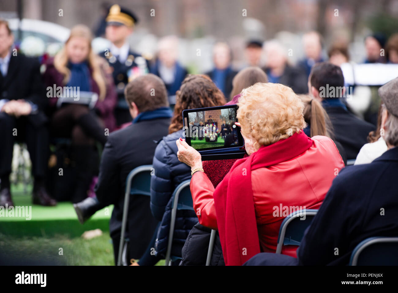 An attendee takes photos of speakers during the Pan Am Flight 103 memorial ceremony in Arlington National Cemetery, Dec. 21, 2015, in Arlington, Va. A terrorist’s bomb destroyed the aircraft 27 years ago, in what became known as the “Lockerbie bombing,” killing 243 passengers, 16 crew members and 11 people on the ground. (U.S. Army photo by Rachel Larue/Arlington National Cemetery/released) Stock Photo