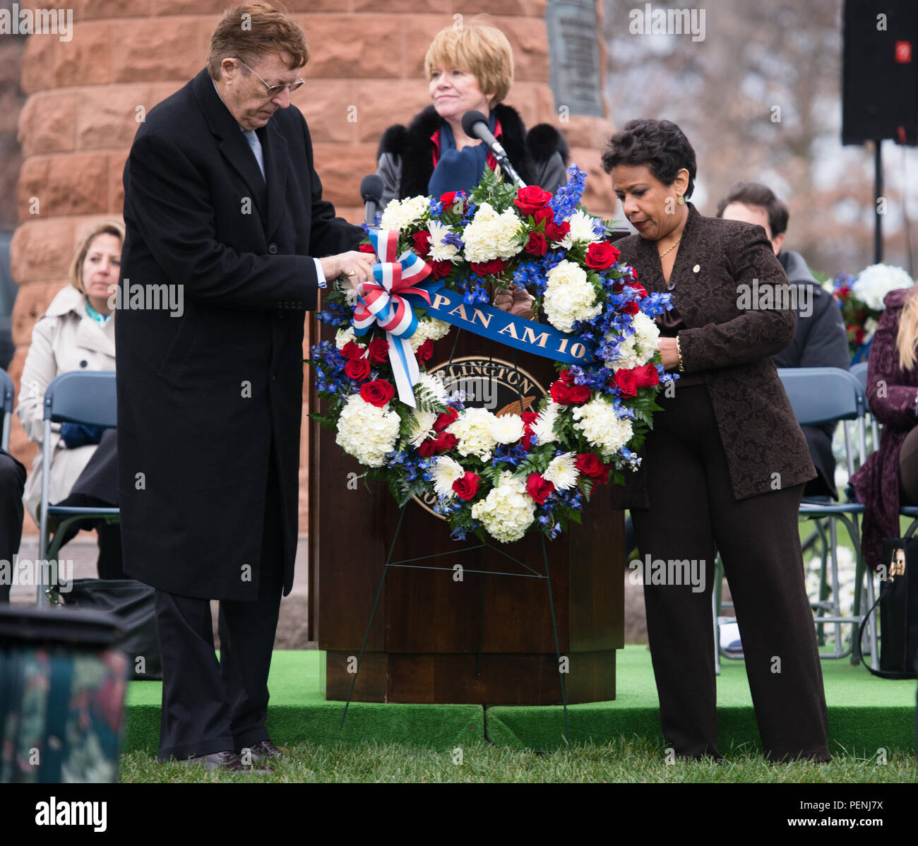 Frank Duggan, left, Victims of Pan Am Flight 103 president, and Loretta Lynch, right, Attorney General of the United States, pick up a wreath to place on the Pan Am Flight 103 memorial in Arlington National Cemetery, Dec. 21, 2015, in Arlington, Va. A terrorist’s bomb destroyed the aircraft 27 years ago, in what became known as the “Lockerbie bombing,” killing 243 passengers, 16 crew members and 11 people on the ground. (U.S. Army photo by Rachel Larue/Arlington National Cemetery/released) Stock Photo
