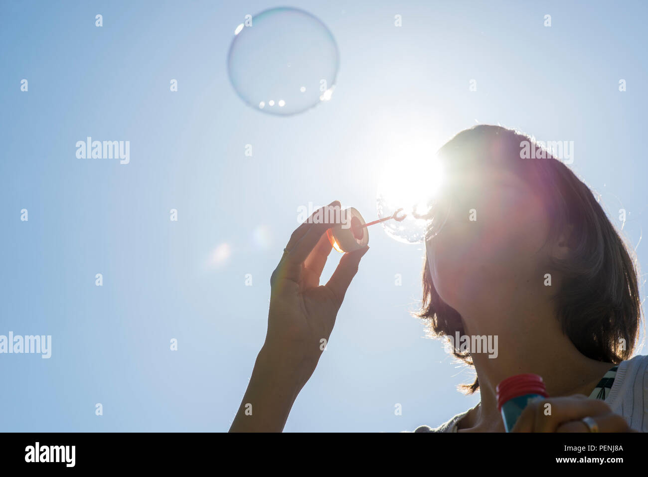 Single Adult Woman With Short Hair Blowing Bubbles Outside With