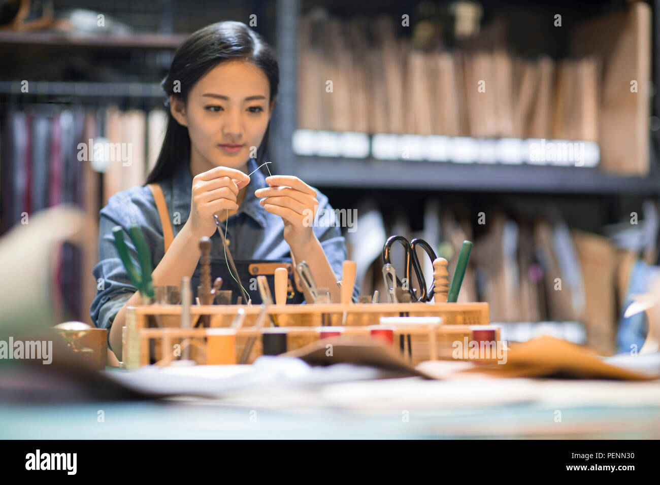 Young leather craftswoman working in studio Stock Photo