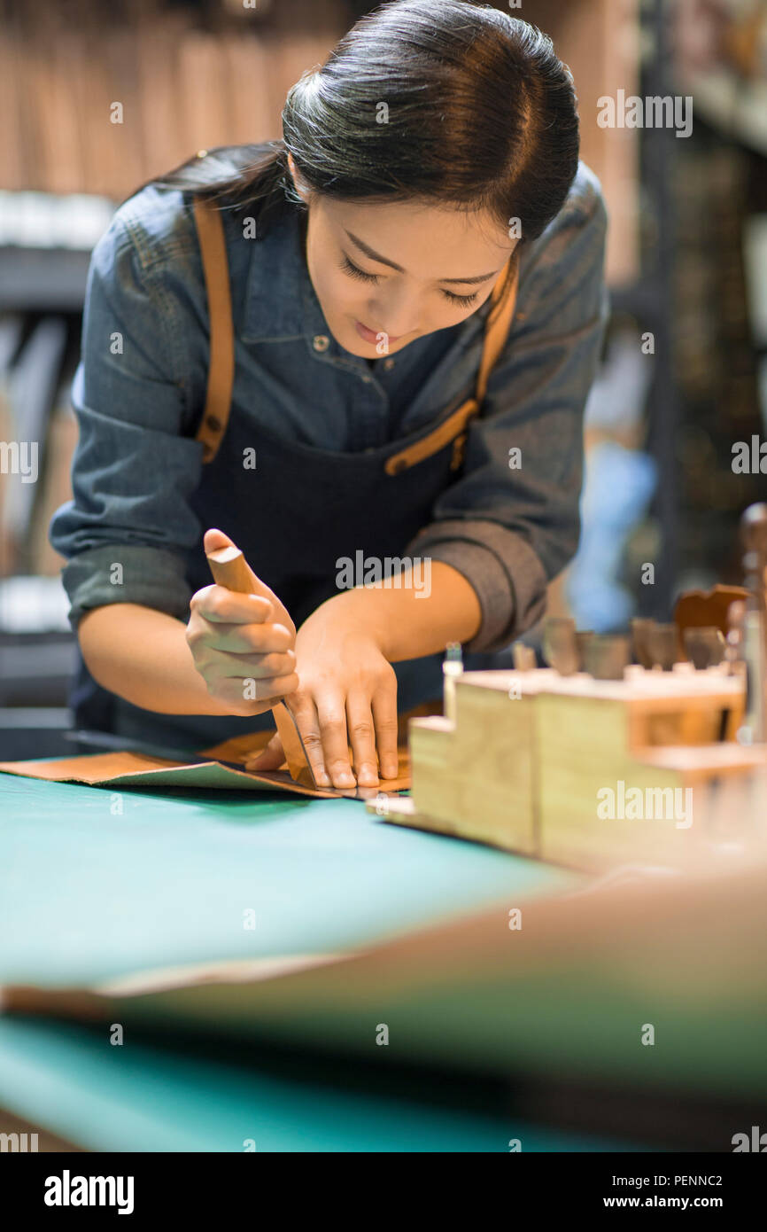 Young leather craftswoman working in studio Stock Photo