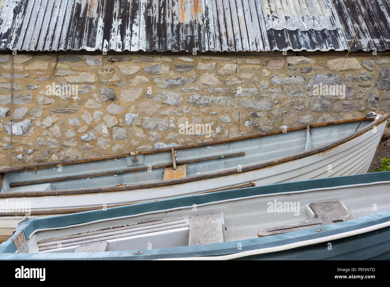 Rowing boats beside a boat shed with a corrugated iron roof on the wild beach of Chapman's Pool, Jurassic Coast, Purbeck, Dorset, England, UK Stock Photo