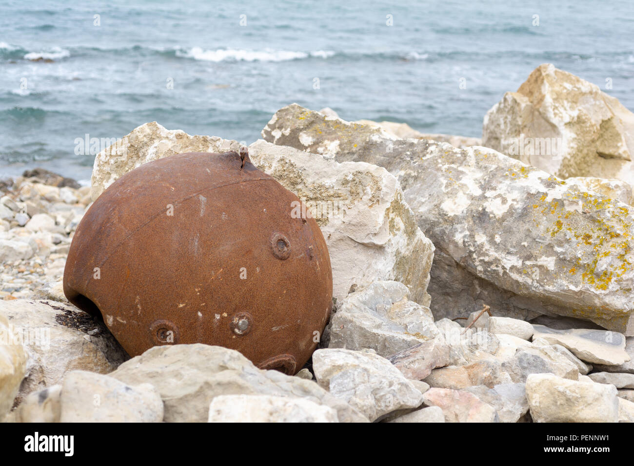 Rusty old sea mine casing on the rocks on the beach Chapman's Pool ...