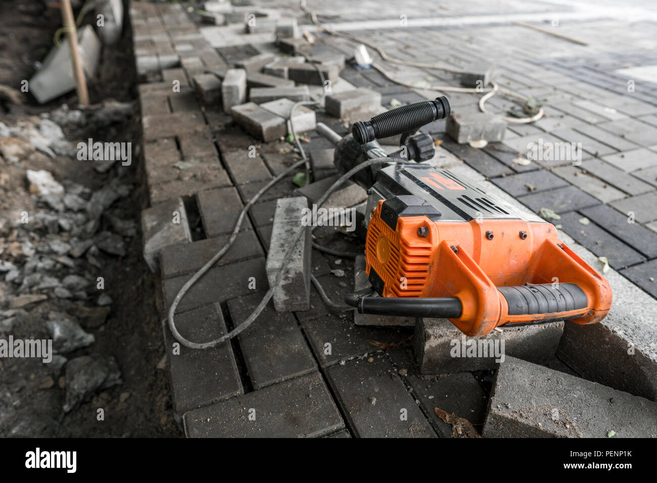 Electric Concrete Breaker laying on a road of cobblestone during sidewalk construction works