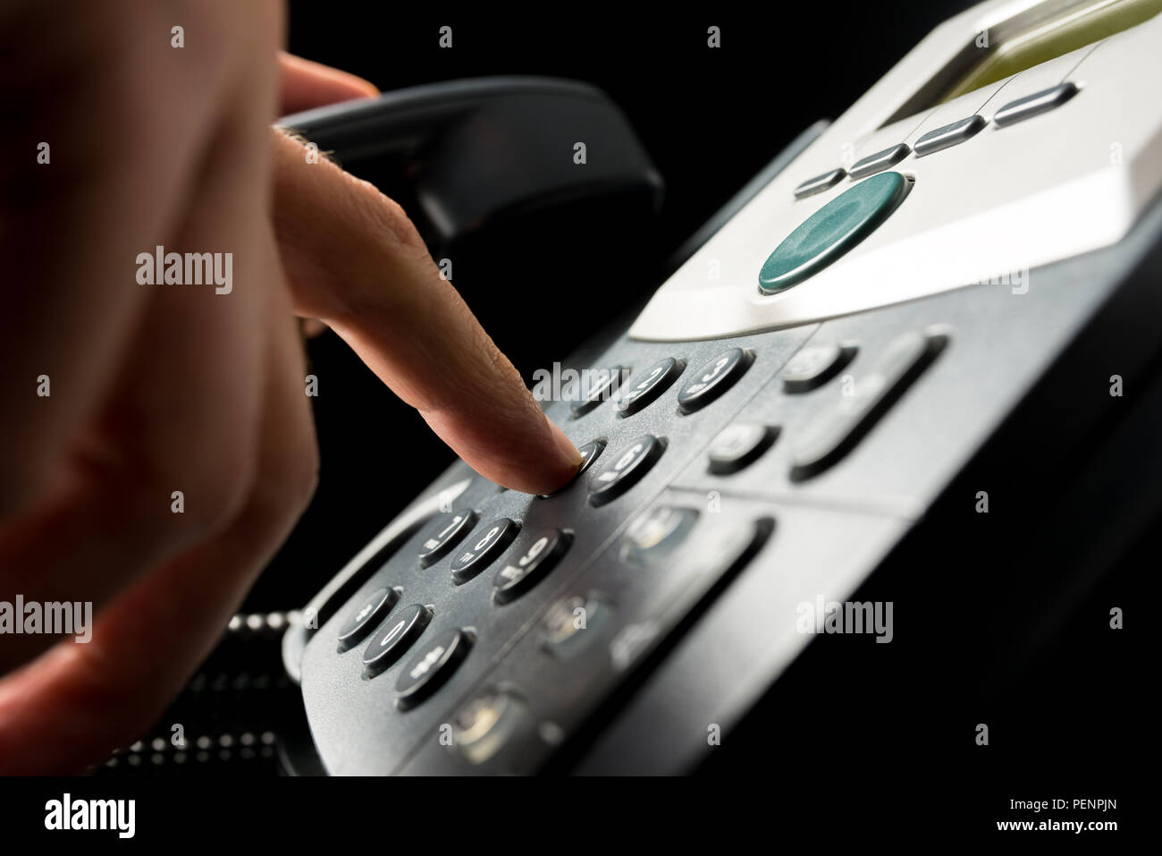 Person dialing out on a landline telephone punching in the numbers on