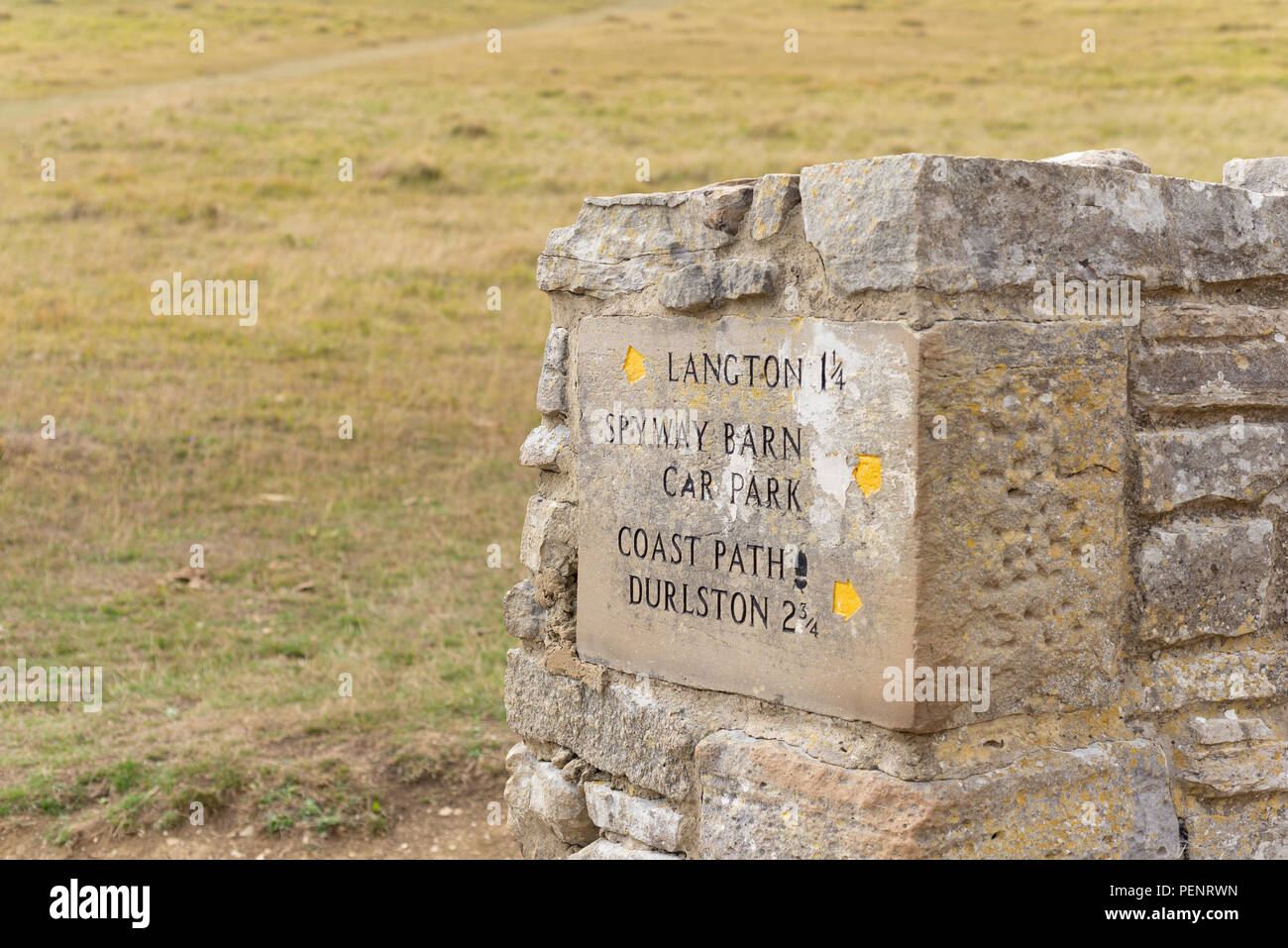 Distances sign carved into a large piece of stone at the end of a wall on the South West Coastal Path at Langton, Dorset, England, UK Stock Photo