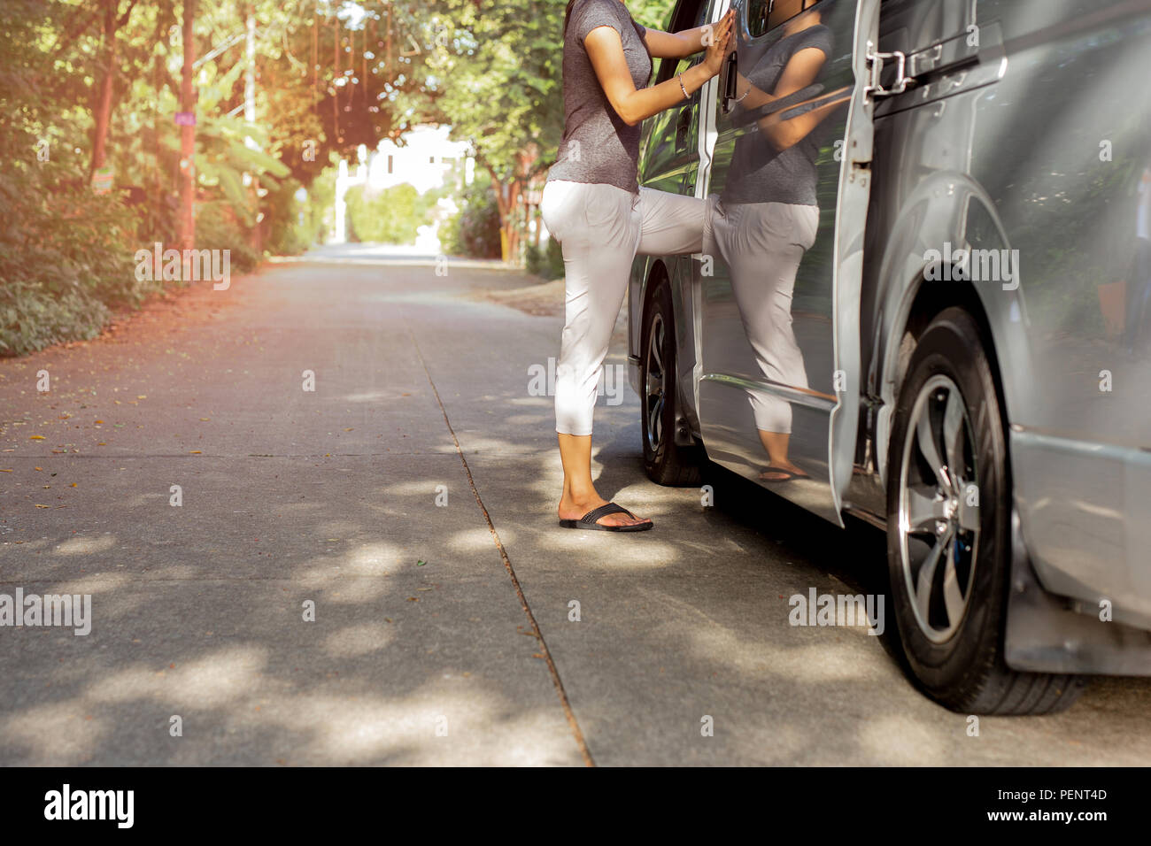 Woman passenger wearing flip flops getting on the bus on vacation. Stock Photo