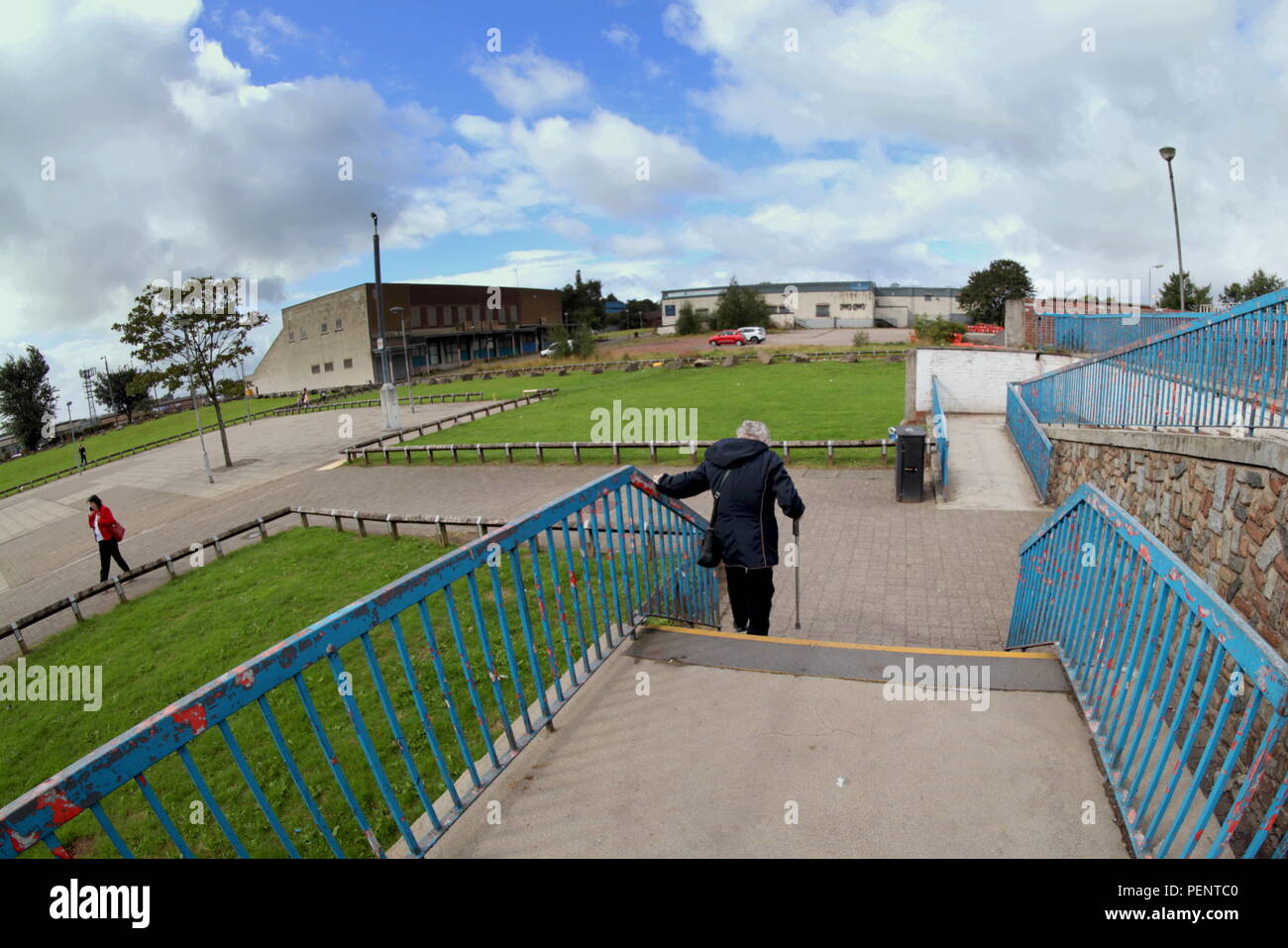 old woman on disability benefits struggling down stairs no disabled access in the deprived peripheral housing scheme of Drumchapel in Glasgow Stock Photo