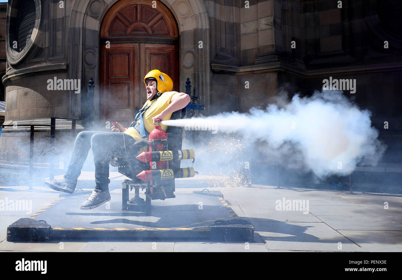 Actor Andy Joyce tests the spinning rocket chair in front of Edinburgh's McEwan Hall which forms part of one of the explosive science experiments that are demonstrated in the Edinburgh Fringe show 'Brainiac Live!'. Stock Photo