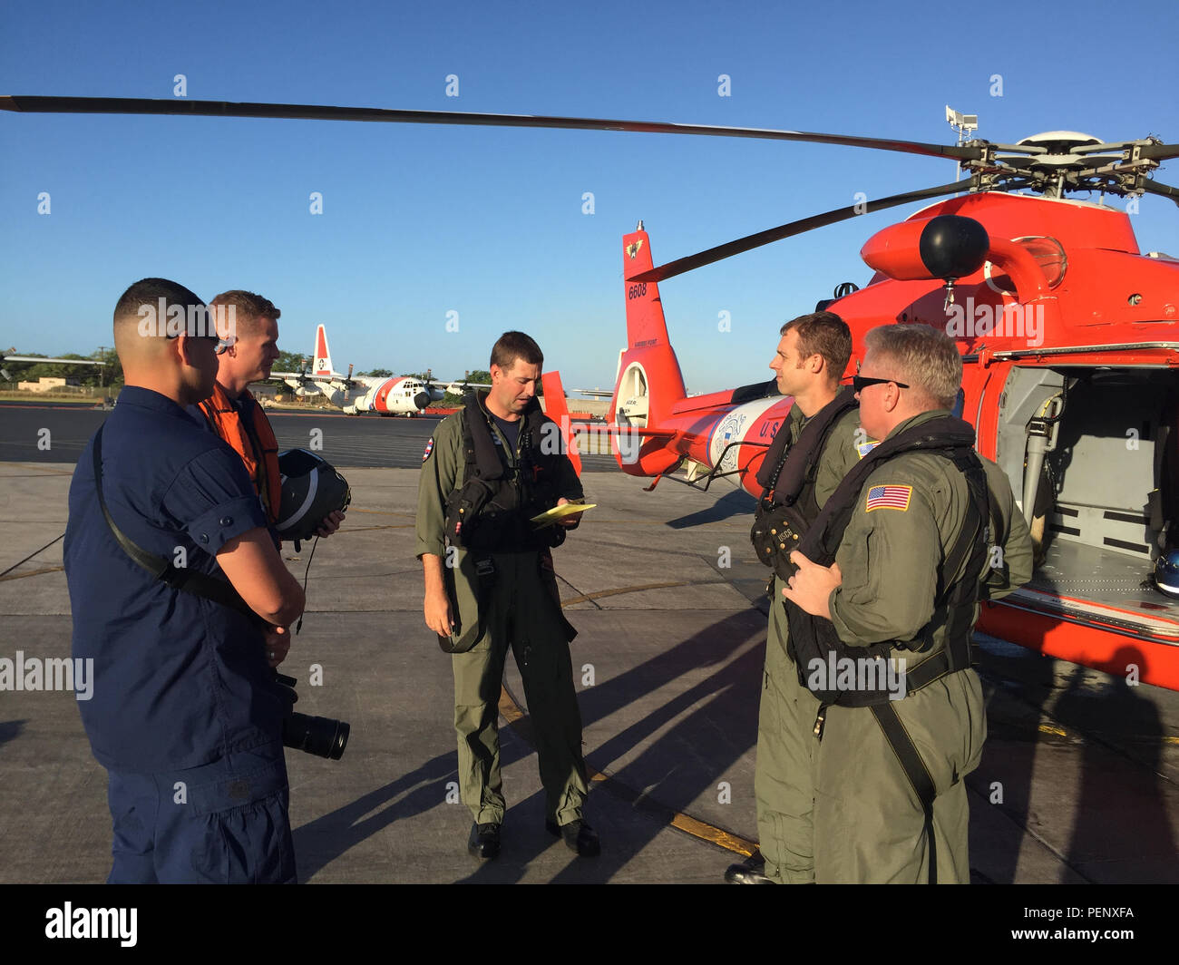 The crew of a Coast Guard MH-65 Dolphin helicopter  (CG 6608) from Air Station Barbers Point conducts a brief prior to take off Jan. 17, 2016. The Dolphin crew relieved the night crew to conduct daytime searches for 12 Marine aviators off the North Shore of Oahu. (U.S. Coast Guard photo by Lt. Sarah Bradley/Released) Stock Photo
