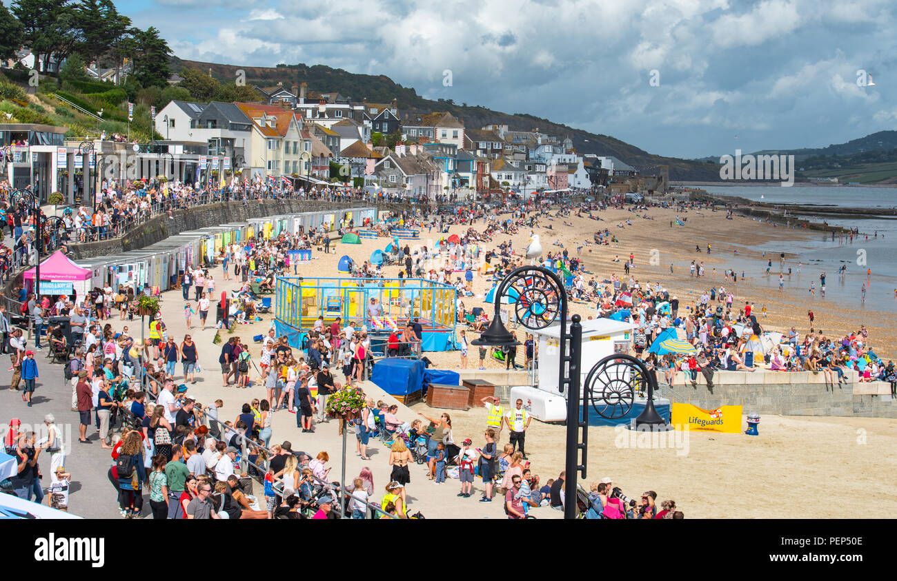 Lyme Regis, Dorset, UK. 16th August 2018.  UK Weather: Warm sunny spells and cloud in Lyme Regis. Crowds of holidaymakers and visitors flock to the beach as the the RAF Falcons military parachute display team drop on to the beach in the coastal resort of Lyme Regis.  The display is one of many events organised today for I Love Lyme Day.  Credit: Celia McMahon/Alamy Live News. Stock Photo