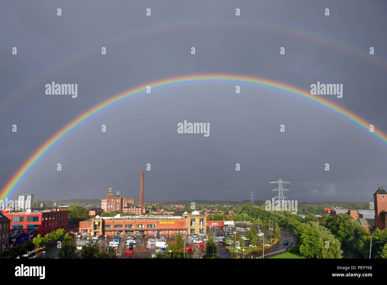 Scotland, UK. 16th August 2018. The double rainbow is over Morrisons at Anchor Mill, Paisley. Double rainbows have a second arc which has it's colours reversed and the second rainbow is due to light being refracted twice on the inside the raindrops. Credit: PictureScotland/Alamy Live News Stock Photo