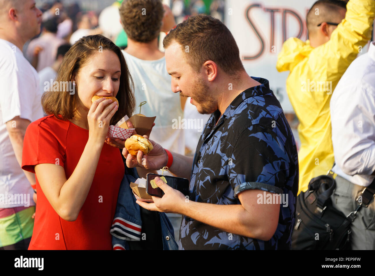 New York, USA. 16th Aug, 2018. A couple eat burgers at Time Out New York's Battle of the Burger 2018 in New York, the United States, on Aug. 16, 2018. Over 100 people attended the event on Thursday to taste and vote for their favorite burgers made by burger vendors across the city. Credit: Lin Bilin/Xinhua/Alamy Live News Stock Photo