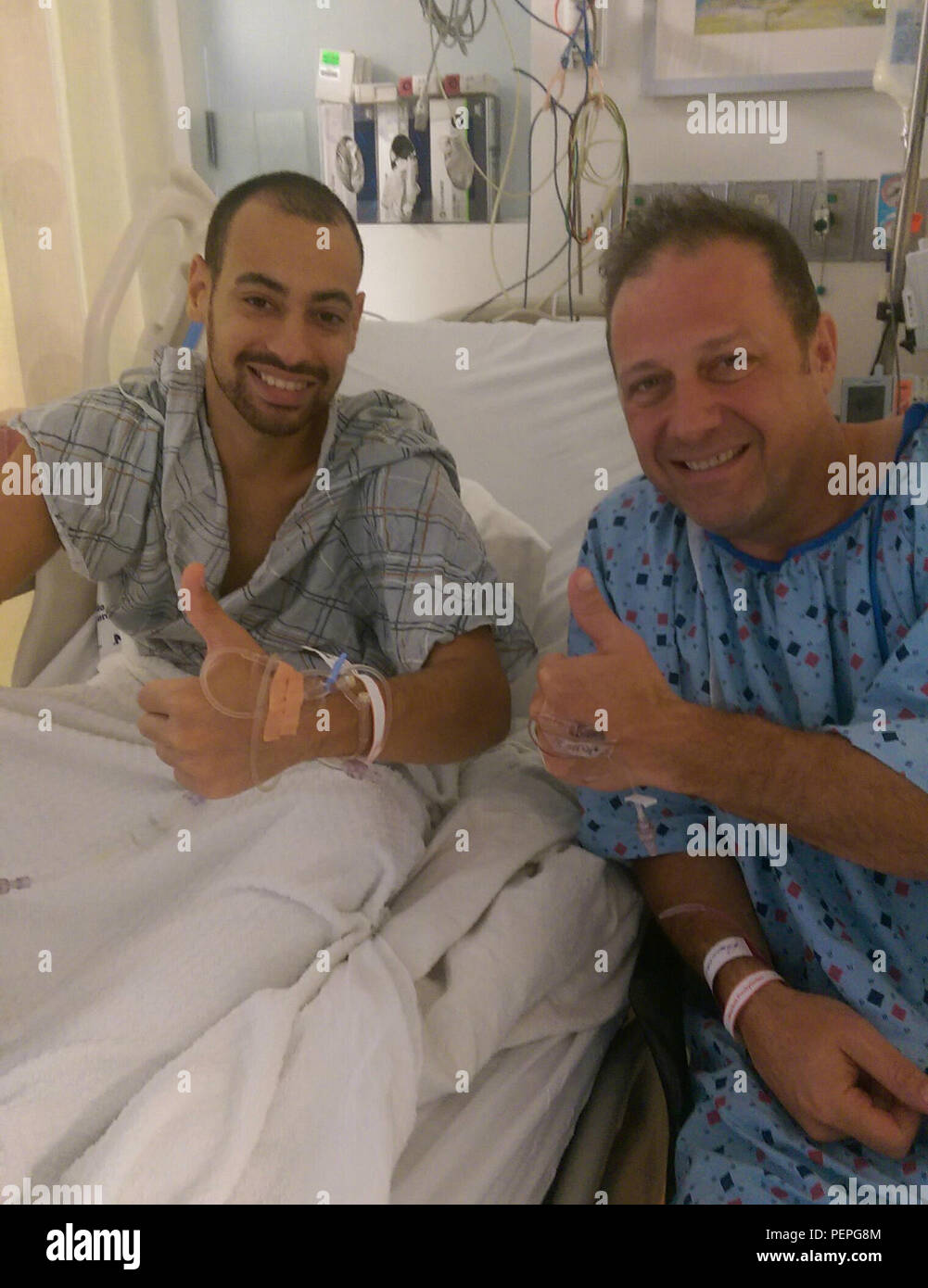 New York Air National Guard Staff Sgt. Daniel Cola (left) and Master Sgt. Henry Windels (right) of the 105th Airlift Wing, give thumbs-up before surgery Oct. 6, 2015, during which  Windels donated one his kidneys to Cola, saving Cola from a difficult, limited life with continual kidney-dialysis treatments. (Photo Courtesy Aly Cola) Stock Photo